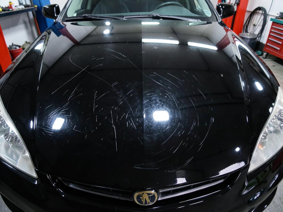 Black hood with swirl marks beside freshly polished paint